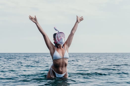 Young happy woman in white bikini put pink snorkeling mask on beach before swimming. girl having fun relaxing on beautiful beach. Beach lifestyle