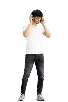 A man, on a white background, in full height, listening to music.