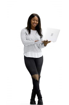 A woman, on a white background, in full height, uses a laptop.