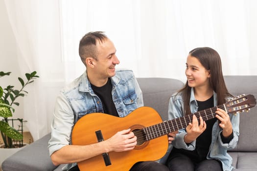 Artistic talented girl showing her latin music teacher the new song she learned to play on the acoustic guitar at home. High quality photo