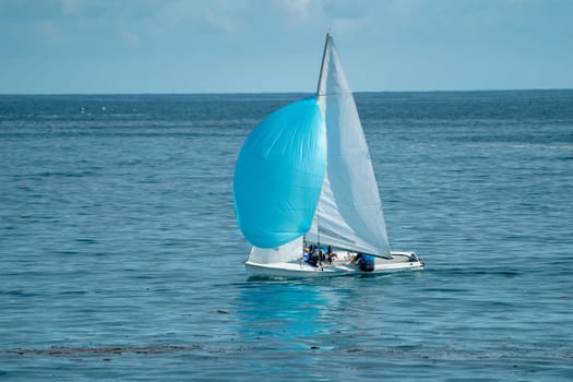 small sailboat on deep blue sea and sky background