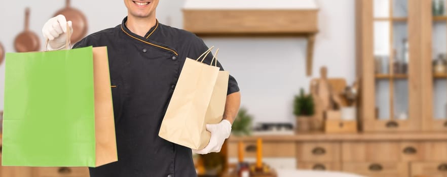 box with fast food being carried by delivery man in uniform for one of clients.