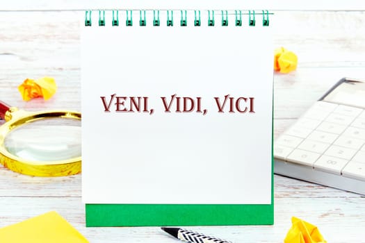 Latin Veni Vidi Vici (I came, I saw, I won) It is written on a standing notebook