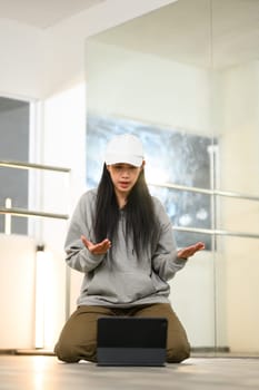 Portrait female dancer having video call on digital tablet while sitting in dance studio.