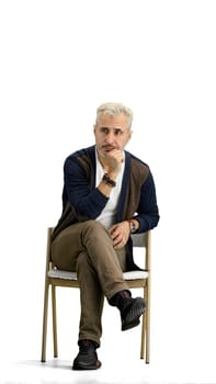 A man, full-length, on a white background, sitting on a chair.
