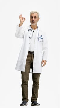 The doctor, in full height, on a white background, shows the ok sign.
