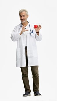 The doctor, in full height, on a white background, shows the heart.