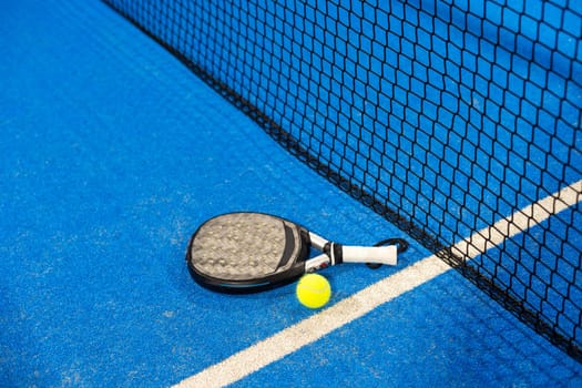 Paddle tennis racket, ball and net on the court . High quality photo