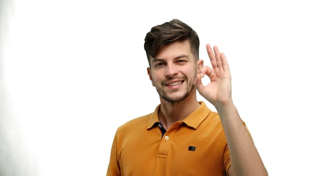 A man, close-up, on a white background, shows an ok sign.