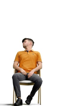 A man, full-length, on a white background, sitting on a chair.