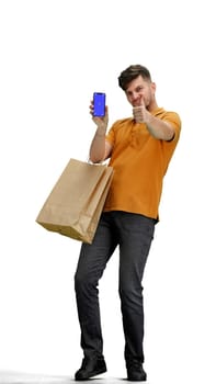 A man, full-length, on a white background, with bags, shows a phone.