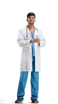 The doctor, in full height, on a white background, uses a phone.