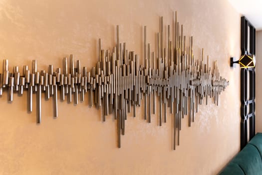 A decorative element for decorating the wall in a cafe or restaurant in the form of an audio signal, made of metal tubes from an audio editor