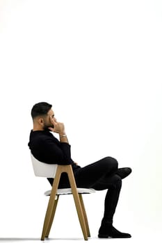 A man, full-length, on a white background, sitting on a chair.