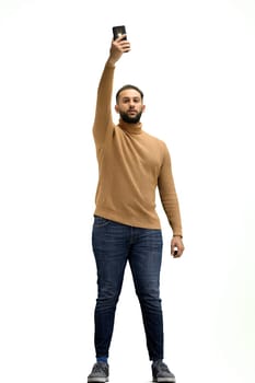 A man, full-length, on a white background, waving his phone.