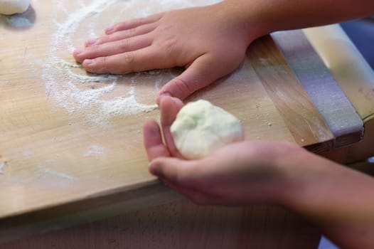 Preparation of homemade fruit dumplings with plums. Czech specialty of sweet good food. Dough on kitchen wooden table with hands.