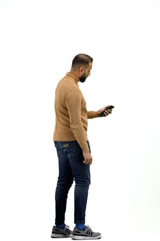 A man, full-length, on a white background, uses a phone.
