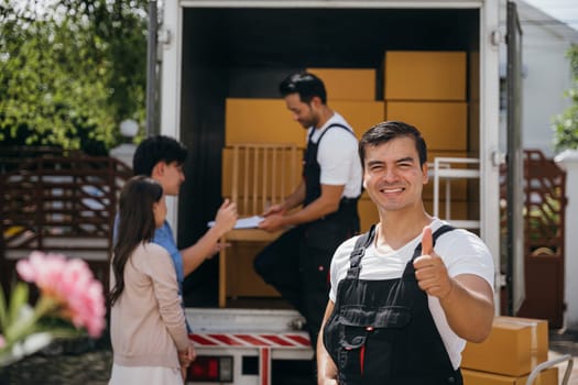 A smiling mover captured in a portrait unloads boxes into a new home from a truck. These removal company workers guarantee efficient moving and happiness. Moving day concept