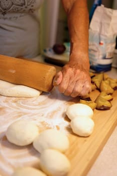 Preparation of homemade fruit dumplings with plums. Czech specialty of sweet good food. Dough on kitchen wooden table with hands.