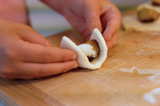 Preparation of homemade fruit dumplings with plums. Czech specialty of sweet good food. Dough on kitchen wooden table with hands.