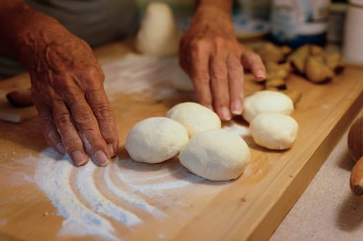 Preparation of homemade fruit dumplings with plums. Czech specialty of sweet good food. Dough on kitchen wooden table with hands.