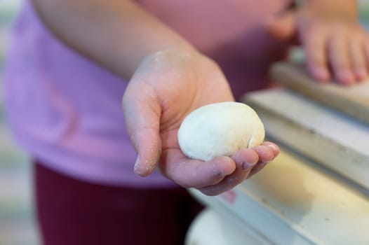 Preparation of homemade fruit dumplings with plums. Czech specialty of sweet good food. Dough on kitchen wooden table with hands.