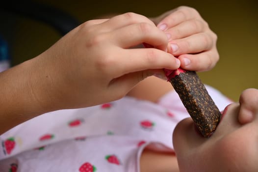 Young girl - child eating candy and sweets. Detail of face and mouth. Concept for healthy lifestyle - healthy - unhealthy sweet food and sugar.