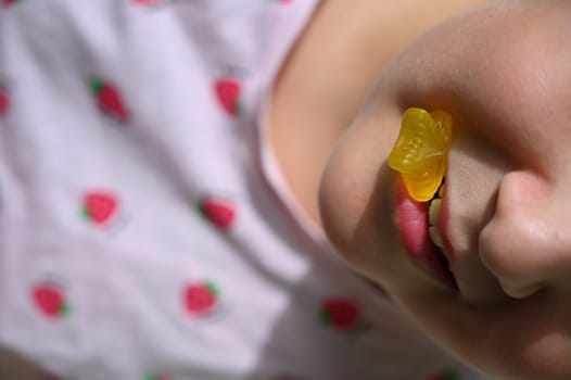 Young girl - child eating candy and sweets. Detail of face and mouth. Concept for healthy lifestyle - healthy - unhealthy sweet food and sugar.