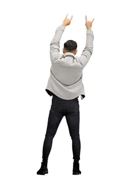 A man, full-length, on a white background, shows the sign of a goat.