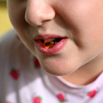 Young girl - child eating candy and sweets. Detail of face and mouth. Concept for healthy lifestyle - healthy - unhealthy sweet food and sugar.