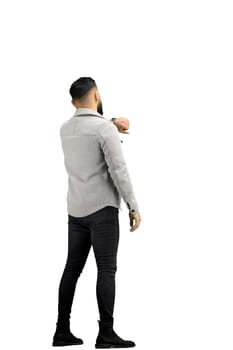 A man, full-length, on a white background, looks at his watch.