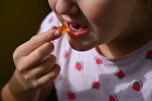 Young girl - child eating candy and sweets. Detail of face and mouth. Concept for healthy lifestyle - healthy - unhealthy sweet food and sugar.