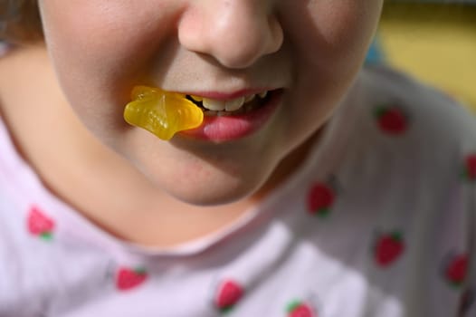 Young girl - child eating candy and sweets. Detail of face and mouth. Concept for healthy lifestyle - healthy - unhealthy sweet food and sugar.