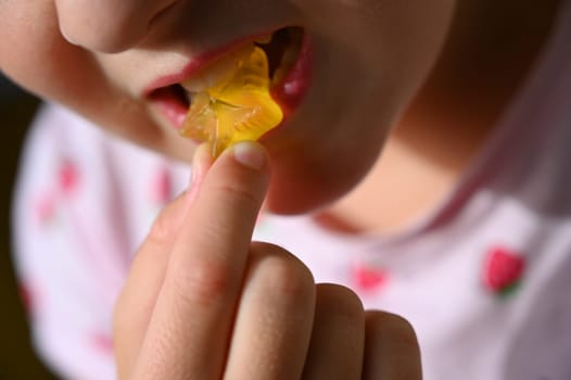 Young girl - child eating candy and sweets. Detail of face and mouth. Concept for healthy lifestyle - healthy - unhealthy sweet food and sugar.