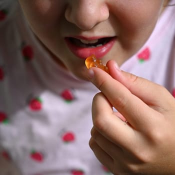 Young girl - child eating candy and sweets. Detail of face and mouth. Concept for healthy lifestyle - healthy - unhealthy sweet food and sugar.