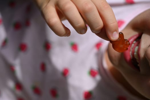 Young girl - child eating candy and sweets. Detail of face and mouth. Concept for healthy lifestyle - healthy - unhealthy sweet food and sugar.