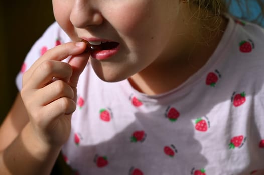 Young girl - child eating candy and sweets. Detail of face and mouth. Concept for healthy lifestyle - healthy - unhealthy sweet food and sugar.