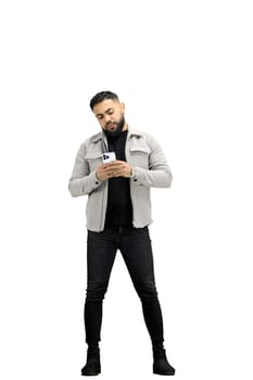 A man, full-length, on a white background, uses a phone.