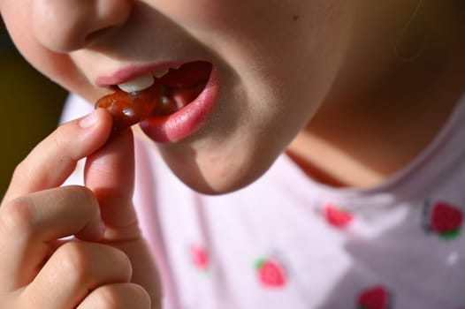 Young girl - child eating candy and sweets. Detail of face and mouth. Concept for healthy lifestyle - healthy - unhealthy sweet food and sugar.