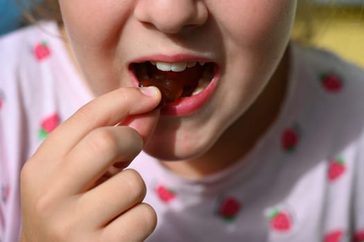 Young girl - child eating candy and sweets. Detail of face and mouth. Concept for healthy lifestyle - healthy - unhealthy sweet food and sugar.