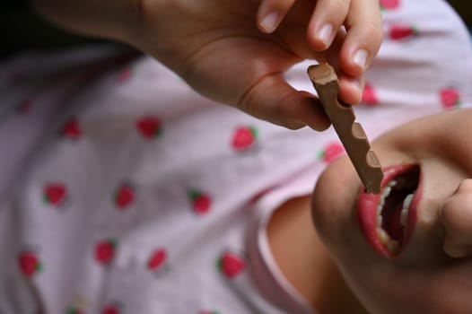 Young girl - child eating candy and sweets. Detail of face and mouth. Concept for healthy lifestyle - healthy - unhealthy sweet food and sugar.