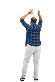 A man, full-length, on a white background, raised his hands up.