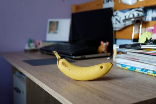 A beautiful fresh banana on a work table at home or in the office with a computer or laptop - notebook.