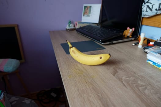 A beautiful fresh banana on a work table at home or in the office with a computer or laptop - notebook.