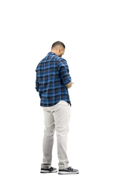 A man, full-length, on a white background, uses a phone.