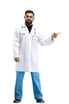The doctor, in full height, on a white background, points to the side.