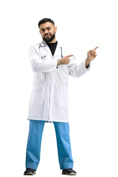 The doctor, in full height, on a white background, points to the side.