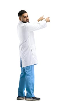 The doctor, in full height, on a white background, points to the side.