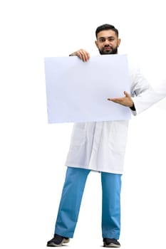 The doctor, in full height, on a white background, shows a white sheet.
