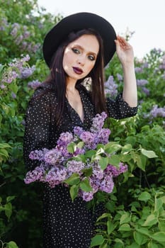 A fashionable girl with dark hair, a spring portrait in lilac tones in summer. Bright professional makeup